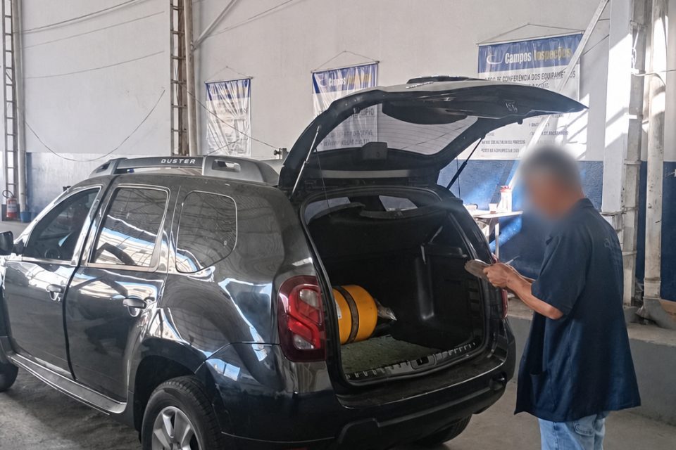 Técnico conferindo o cilindro de GNV no porta-malas de um veículo