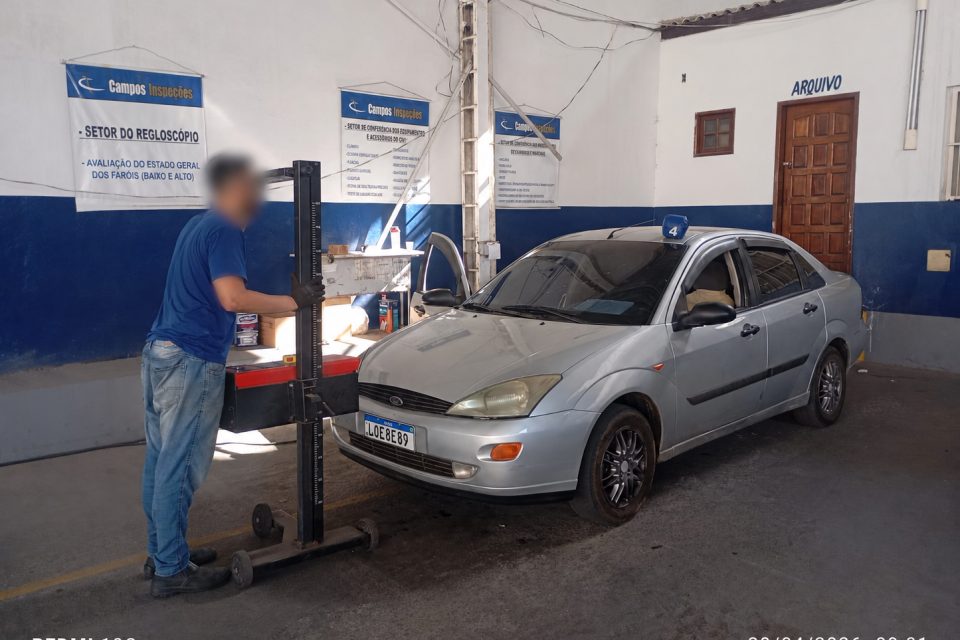 Técnico operando o regloscópio diante de um automóvel
